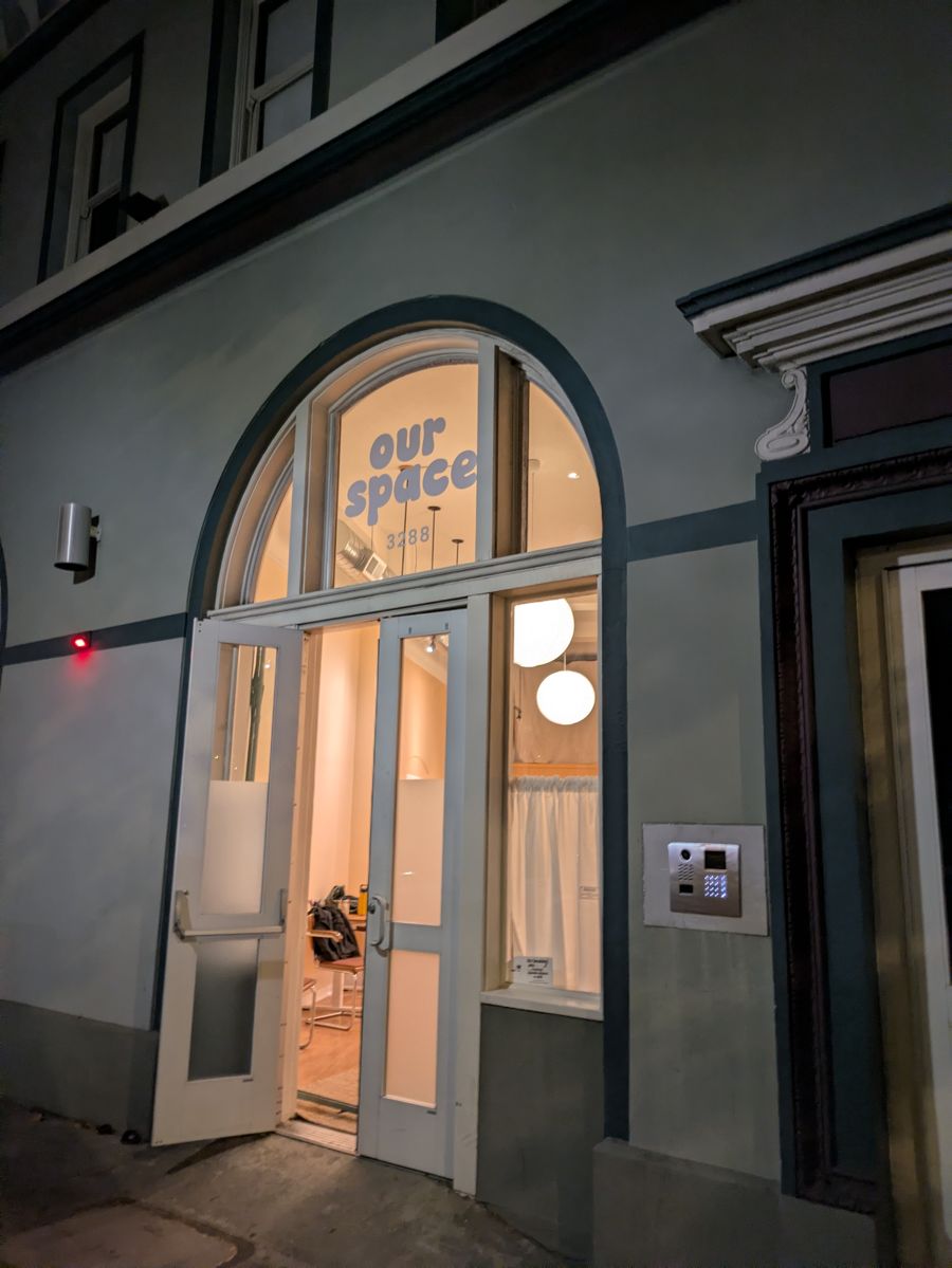 Our Space Berkeley at 3288 Adeline Street at dusk, doors open and lit from inside