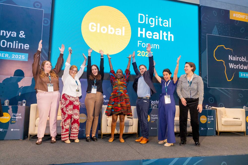 Speakers celebrating on stage in front of the Global Digital Health Forum backdrop